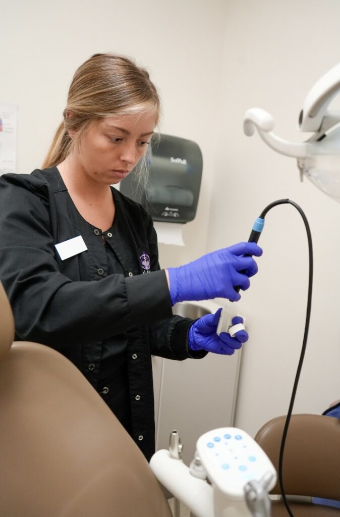 A dental assistant taking a water sample from a dental unit water line.